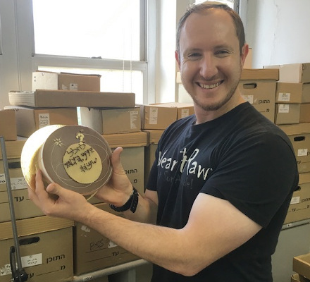 Hillel holding a cake decorated with ancient Hebrew writing